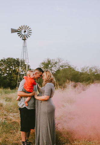 Couple posing with pink smoke to announce having a baby girl
