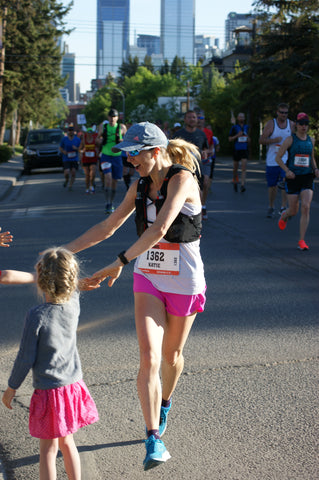 woman marathoner high fiving her kids