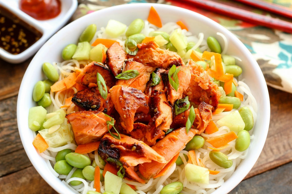 Asian Style Salmon Noodle Bowl is a quick and easy dinner idea with sockeye salmon marinated and pan seared over rice noodles with edamame, carrots, and cucumbers.