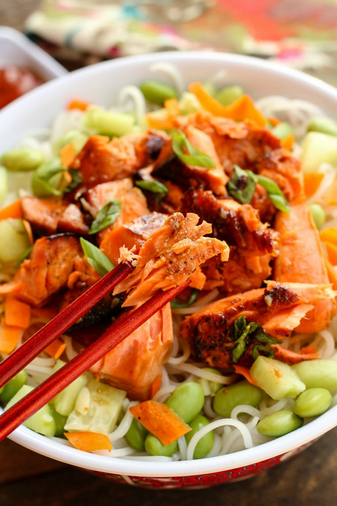 Asian Style Salmon Noodle Bowl is a quick and easy dinner idea with sockeye salmon marinated and pan seared over rice noodles with edamame, carrots, and cucumbers.