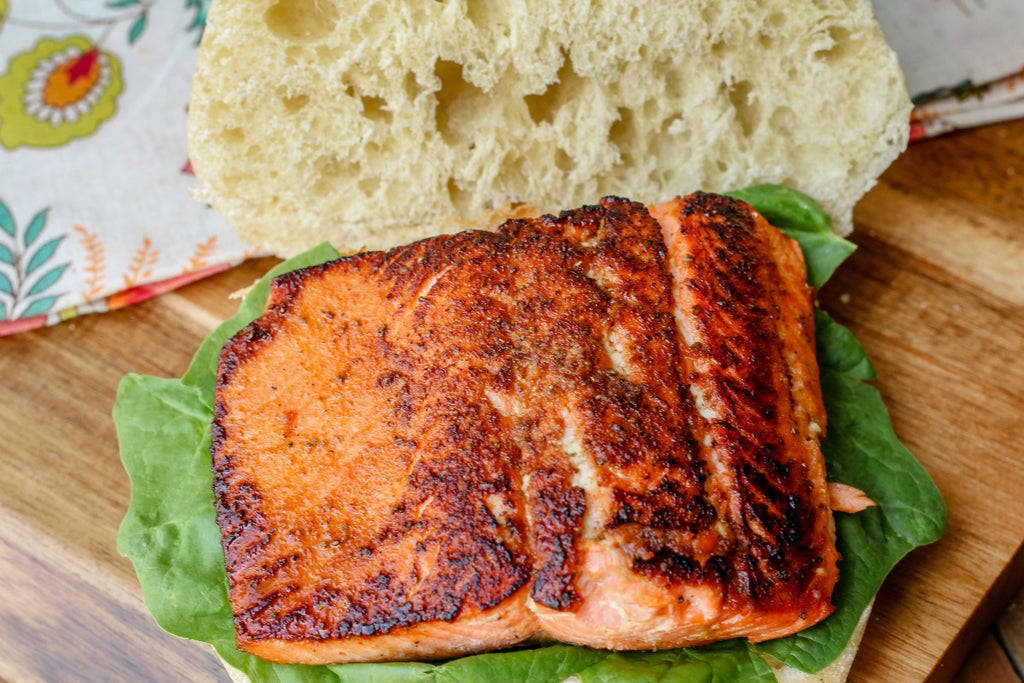 Tomatillo Corn Salmon Sandwich combines unique ingredients like a tomatillo corn relish, sustainable sockeye salmon, and Old Bay seasoning for one tasty nosh. 