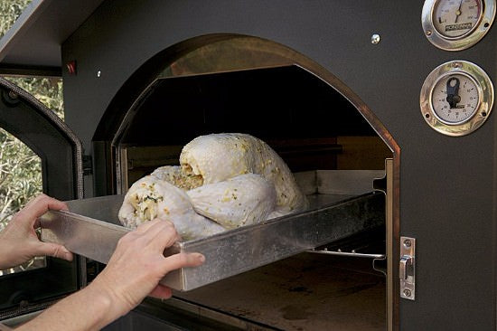 Placing turkey in the Fontana wood-fired oven 