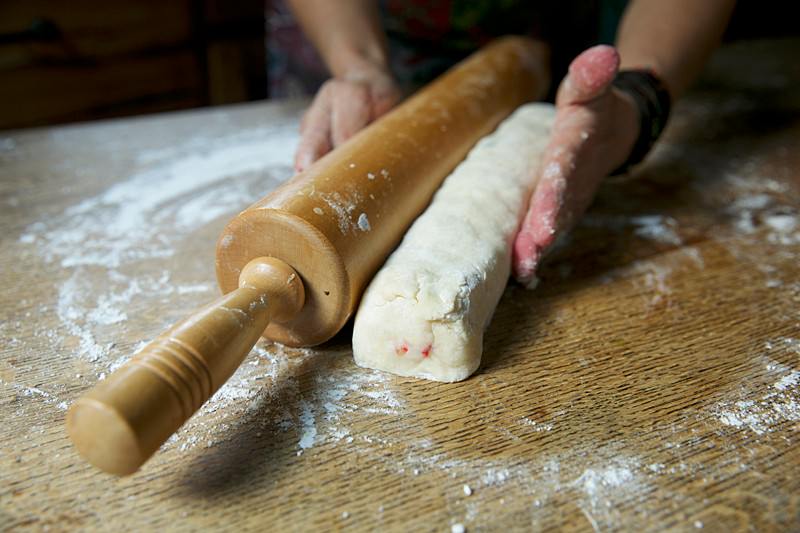 By placing the rolling pin on the side of the dough, you can straighten the block of dough before cutting.