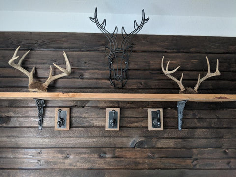 mud room dark stained ship lap wall with decorative deer horns and hooks