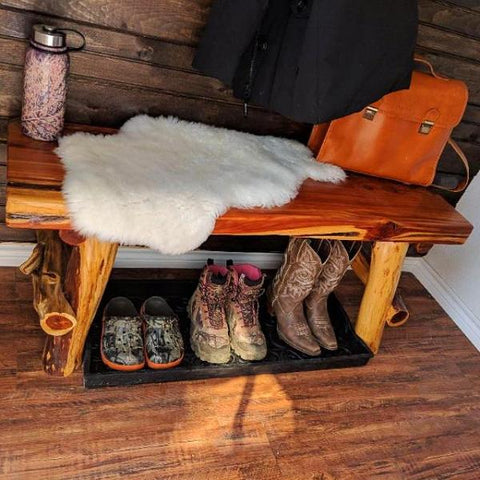Boots under bench inside a neat rustic mud room