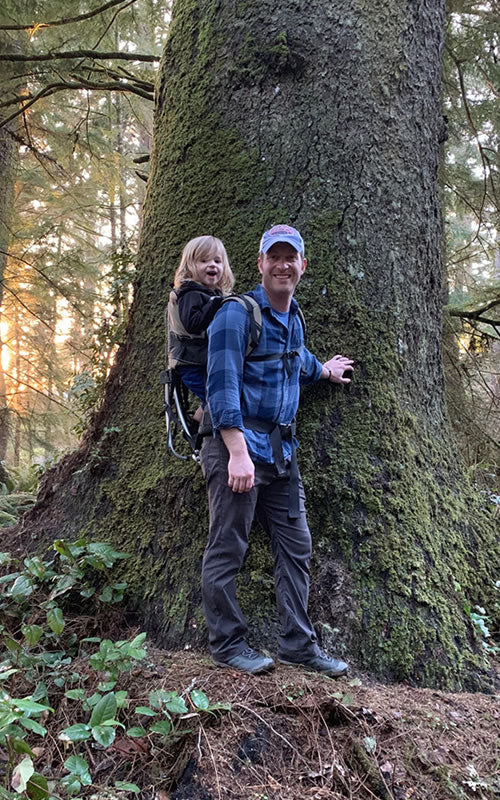 Man and son standing by large tree