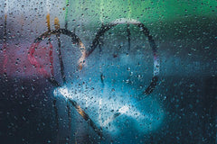 Condensation on window glass make raindrops glow.  Someone has traced a heart shape on the inside of the glass with their finger.