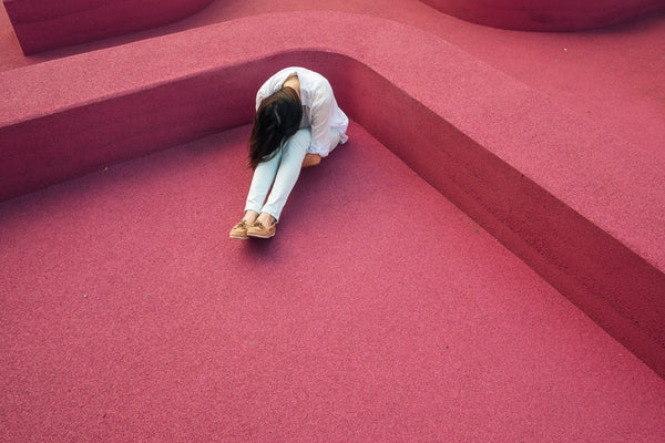 woman on a red floor with her head between her knees