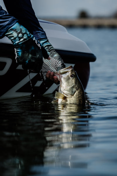 Man Pulling Largemouth Bass Out of Water | Huk Performance Fishing