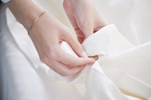 Female putting blanket into white Knotte duvet with brown button attachment