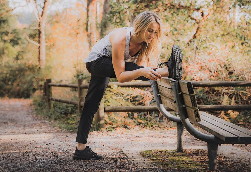 Chelsea Williams streching on a park bench