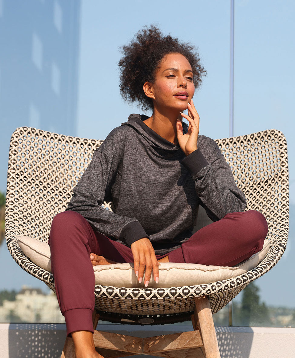 Mondetta female model relaxing in a wicker chair in a melange sweatshirt and joggers