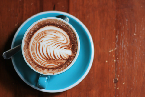 kahverengi masa üstünde mavi fincanda cappucino