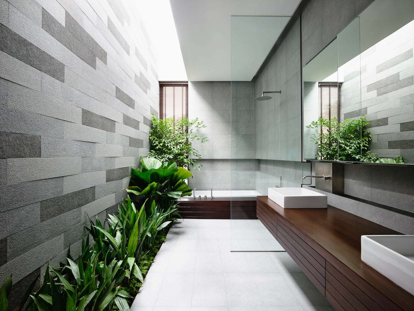 Green plants not only improve the air in interiors, but actually serve as decorative elements, too. This modern spacious bathroom is visually complemented by a mix of different types of leaves – big round, small ones, and those shaped like lancets.