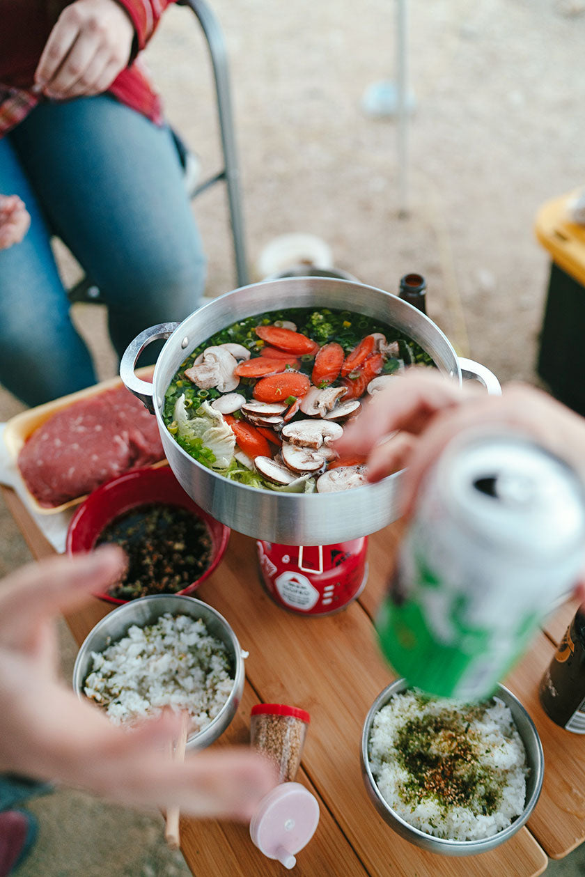 Japanese hot pot cooked on a little gas burner. Rice in bowls on the table next to it. (Photo: Karissa Hosek & Linhbergh Nguyen)