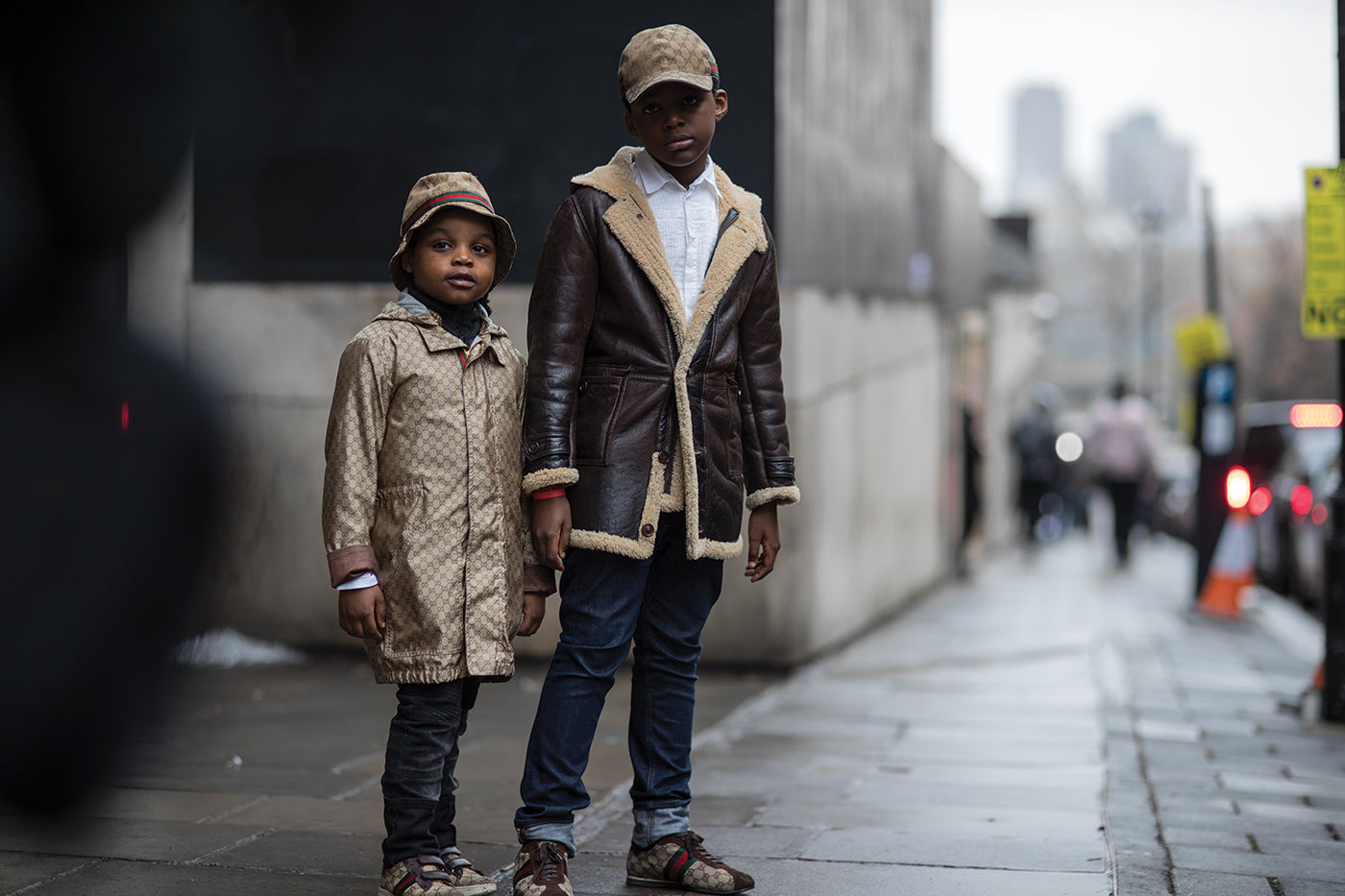 Two children standing on a sidewalk dressed in Gucci jackets in the streets of London. (Photo: Eva Losada)