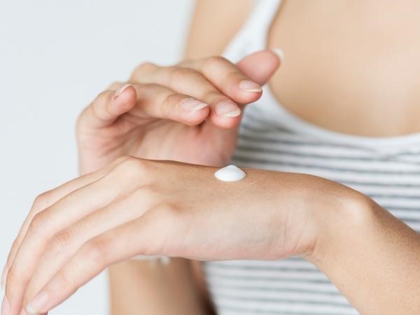 a woman applying lotion to her hands