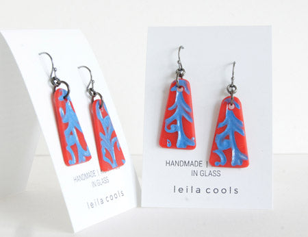 Bold and colorful red and blue dangle earrings with an art nouveau vine design, handmade in glass by Leila Cools.