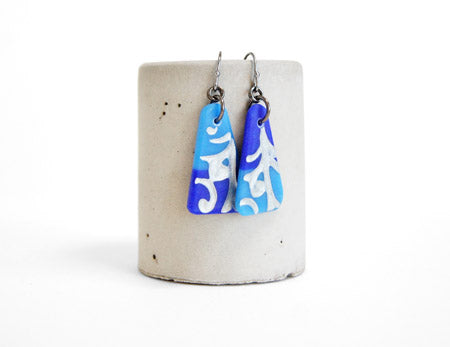 Bold and colorful drop earrings in aquamarine and royal blue, with an art nouveau vine design detailed in silver. Handmade in glass by Leila Cools.