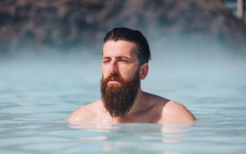 A man with a full beard swimming in the sea.