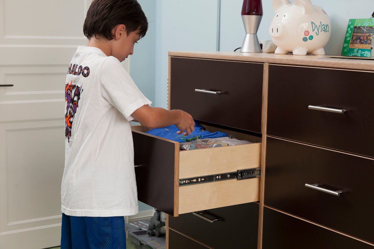 Child with obscured face reaches into an open drawer.