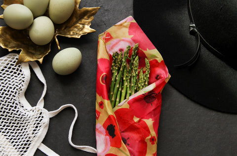 farmers market blue eggs, a net shopping bag, a blag sunhat, and baby asparagus in a poppy-print z wrap