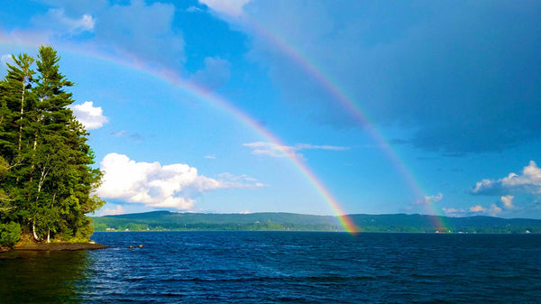 A double rainbow over a lake, with mountains in the background