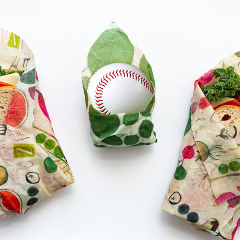 A silly picture of a baseball wrapped in a leafy green print Z Wrap, flanked by a sandwich in Farmer's Market design on the left and right