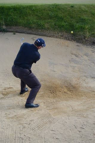 Mark Holland hitting a yellow golf ball out of sand