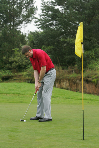 Karl Morris hitting a golf ball towards a yellow flag