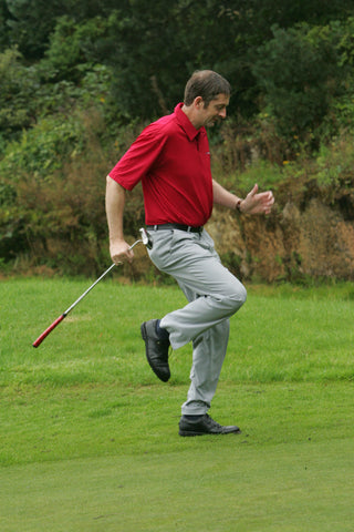 Karl Morris running on the spot with a golf club, in a red shirt.