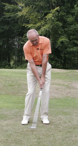 Kieth Williams swinging a golf club in an orange shirt