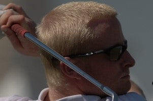 Simon Dyson wearing sunglasses with a golf club behind his head.