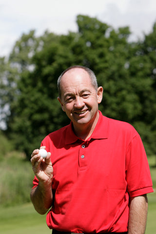 Denis Pugh profile in a red shirt holding a golf ball.