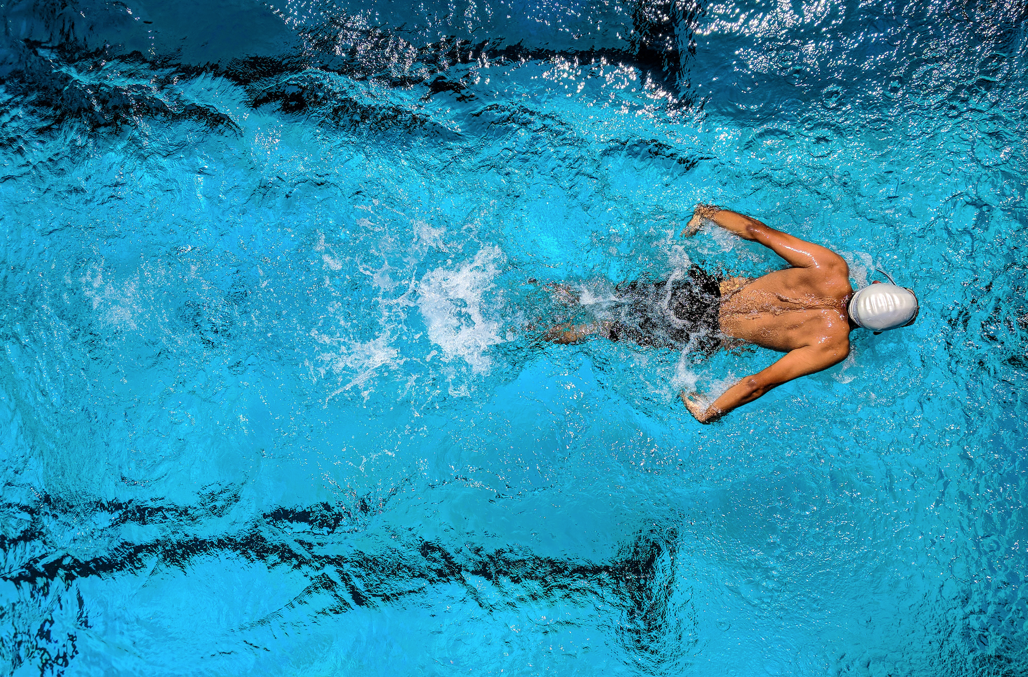 Male triathlete displaying intense focus and impressive endurance while swimming, thanks to a well-balanced marathon nutrition diet