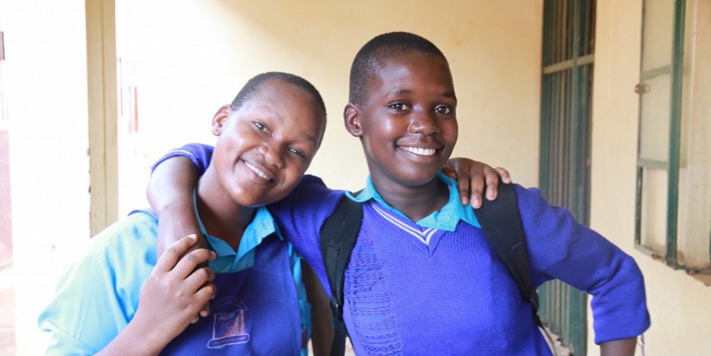 Two teenage girls from a school in Uganda in an embrace