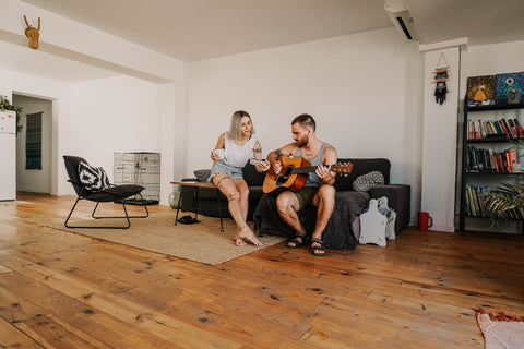 couple sitting on couch. man playing guitar.