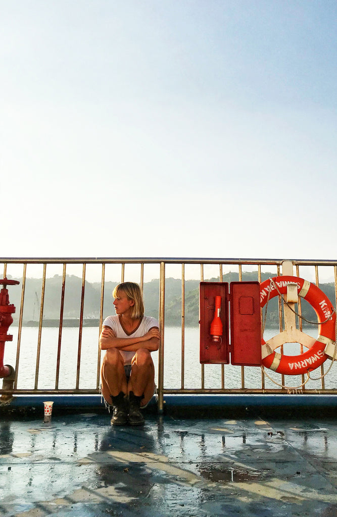 Woman sitting on the floor leaning against a ferry metal railing