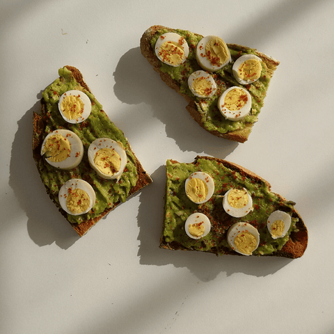 Sourdough bread topping with quail eggs, avocado and coarse red pepper