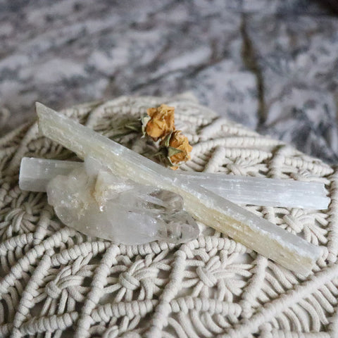 A macrame pillow with dried flowers, Selenite sticks, and Raw Clear Quartz on it