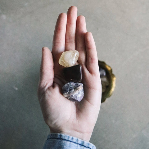 Open hand holding three small tumbled crystals