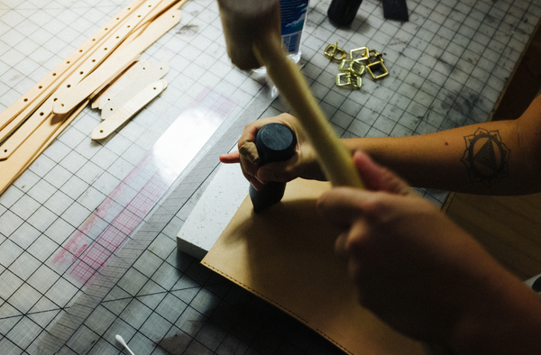 person hammers logo into leather