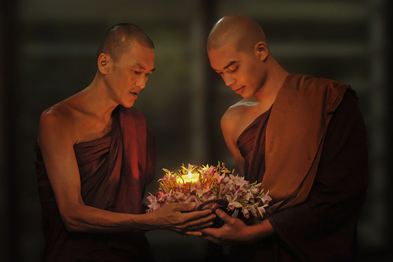 Monks praying while holding a candle together