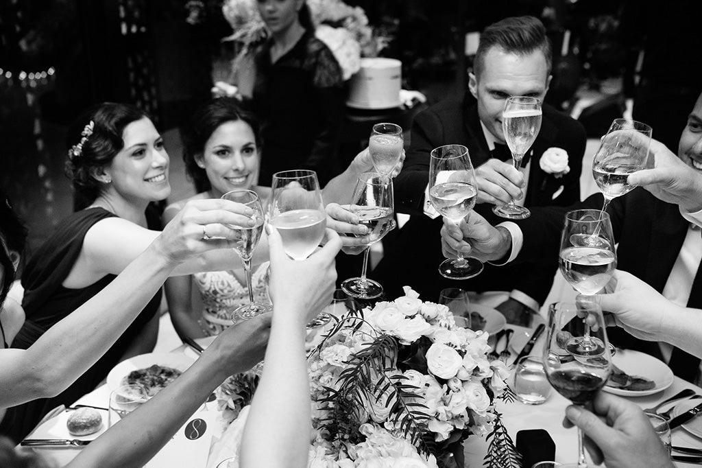 Wedding party toasting around table with wedding flowers as centrepiece