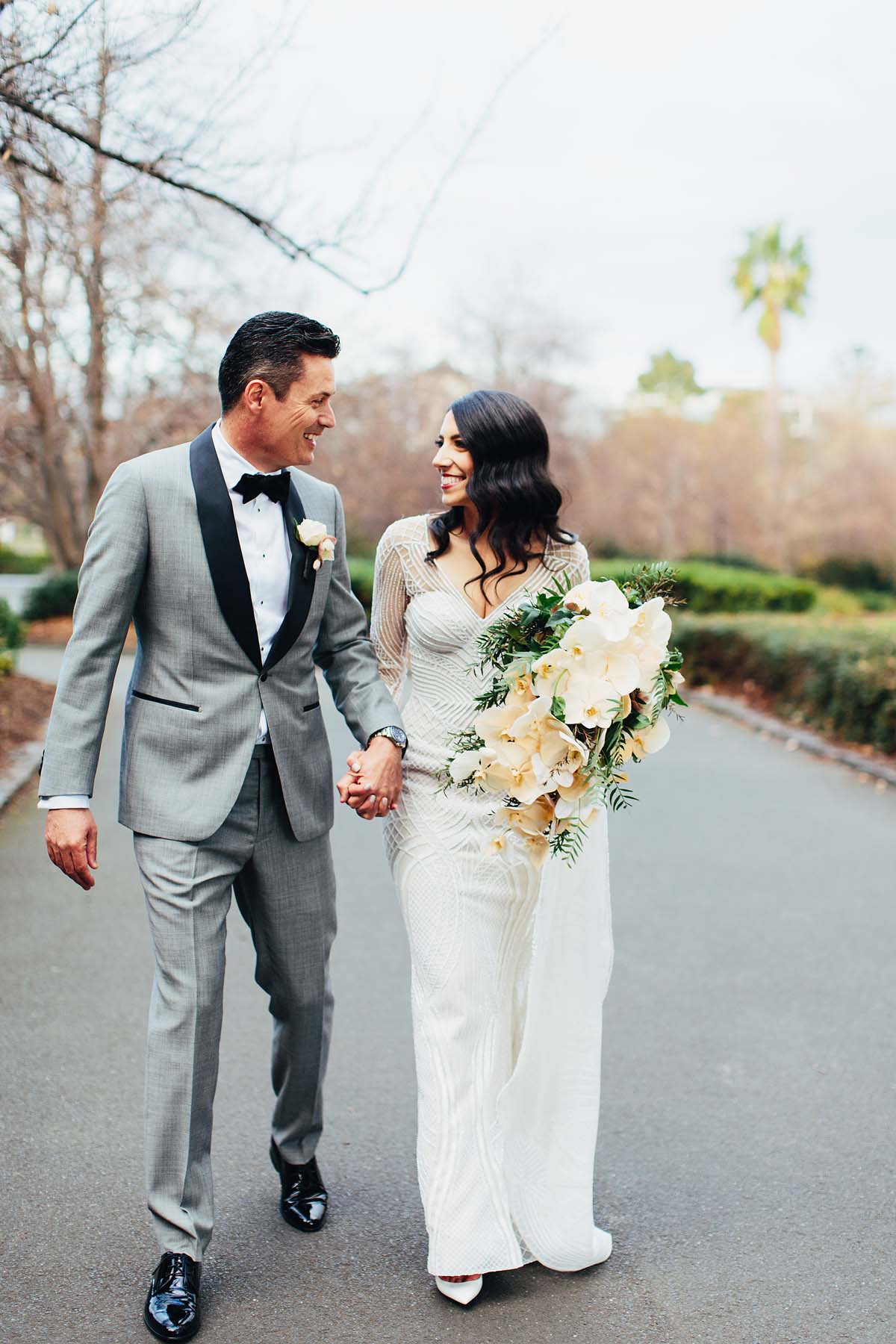 Bride and groom walking while holding wedding flowers