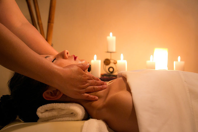 Woman being massaged with candles burning