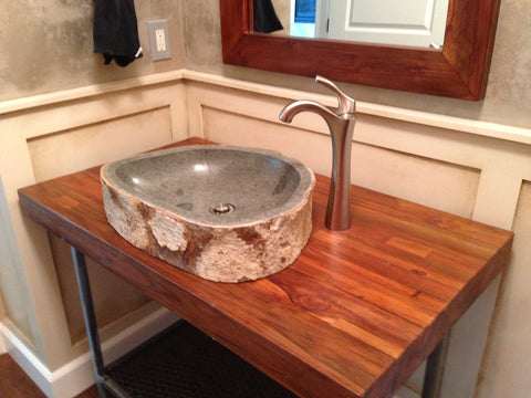 An andesite stone vessel sink in a powder bathroom installed on a custom teak and steel vanity from Impact imports in Boise Idaho.
