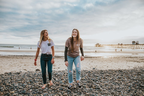 Two friends walking on a beach laughing