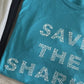 Close up of aqua Save The Sharks Short-Sleeve Unisex T-Shirt reads "Save The Sharks." - getpinkfit - Ethically and Sustainably Made - 10% donated to Oceana shark conservation