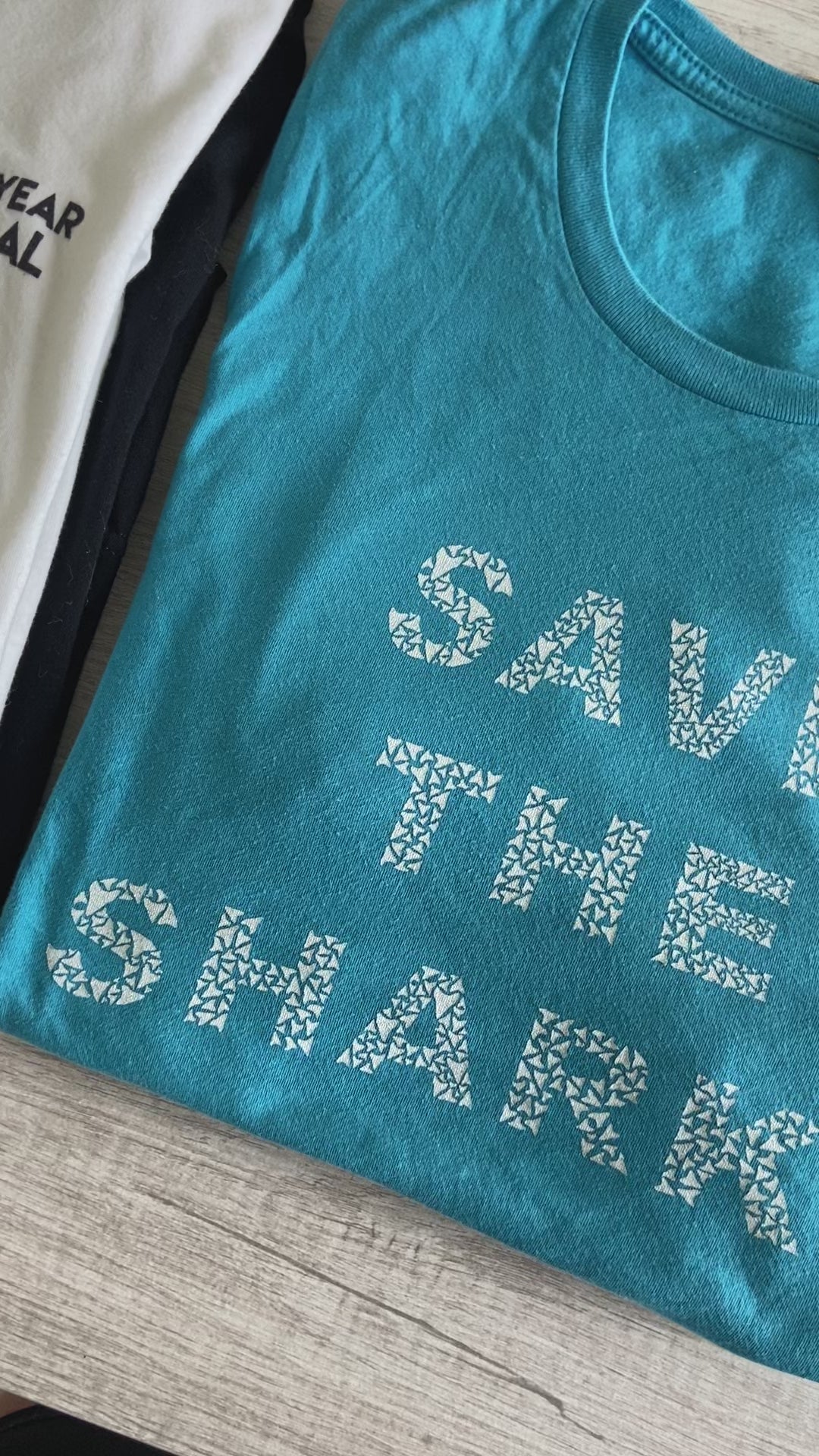 Close up of aqua Save The Sharks Short-Sleeve Unisex T-Shirt reads "Save The Sharks." - getpinkfit - Ethically and Sustainably Made - 10% donated to Oceana shark conservation